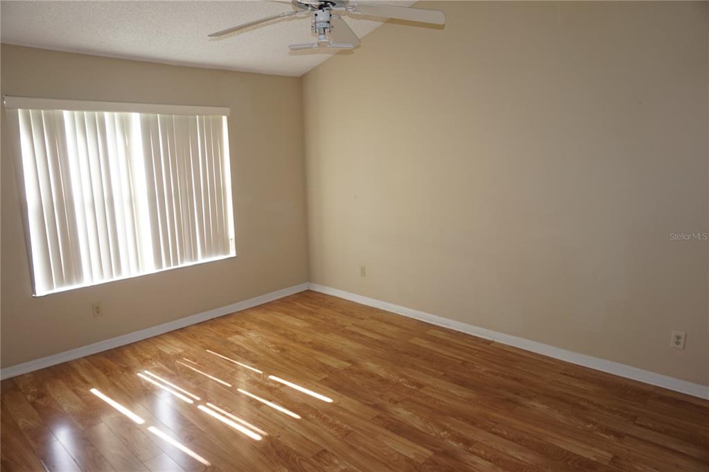 An empty bedroom features light-colored walls, wood-look flooring, a ceiling fan, and vertical window blinds — 2749 N POINCIANA BOULEVARD UNIT 24, KISSIMMEE, FL