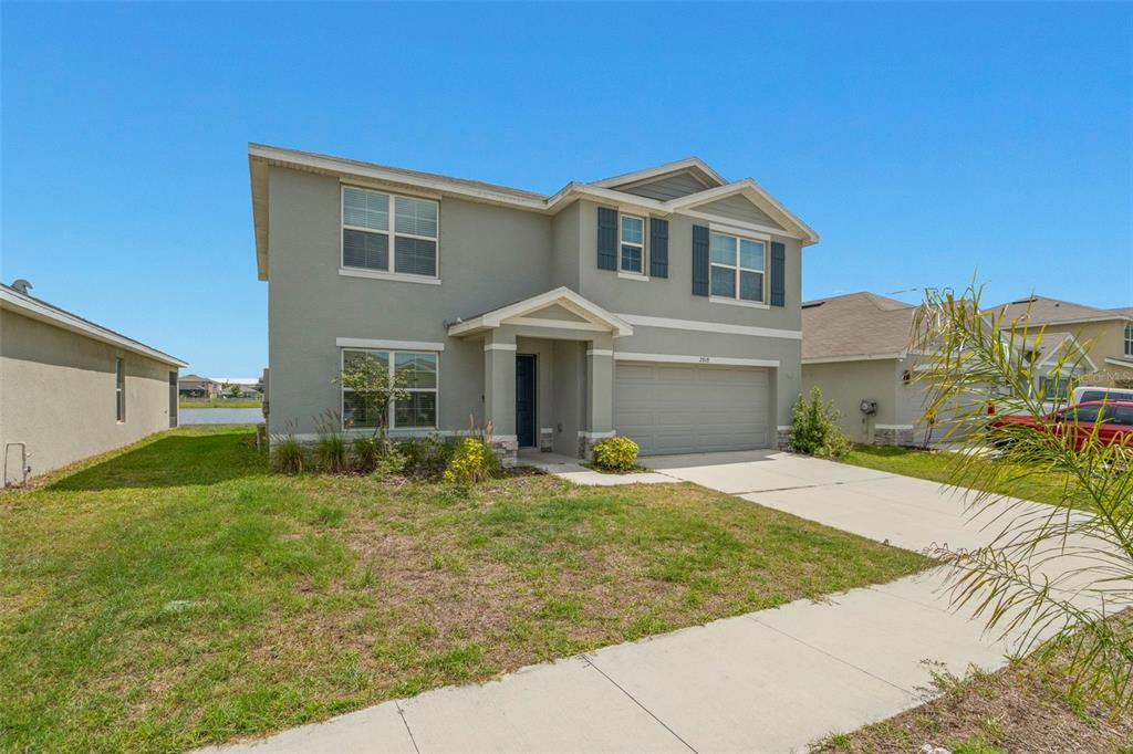 An open-concept living room and kitchen featuring light green walls, neutral furniture, and tile flooring — 2818 GUMBO LIMBO DRIVE, WIMAUMA, FL