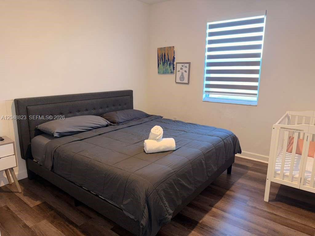 A bedroom features a gray tufted bed, a white crib, and a window with blinds — 13623 SW 184th Ter, Miami FL 33177, MIAMI, FL