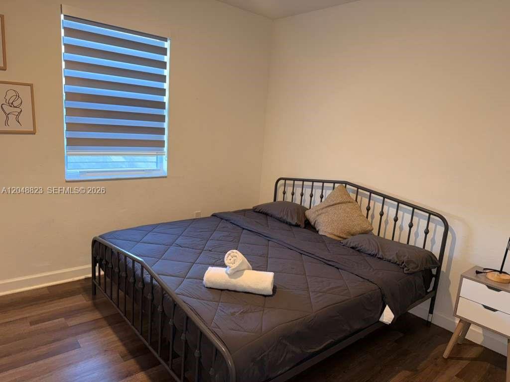 A bedroom features a dark metal bed frame, dark bedding, and a window with blinds — 13623 SW 184th Ter, Miami FL 33177, MIAMI, FL