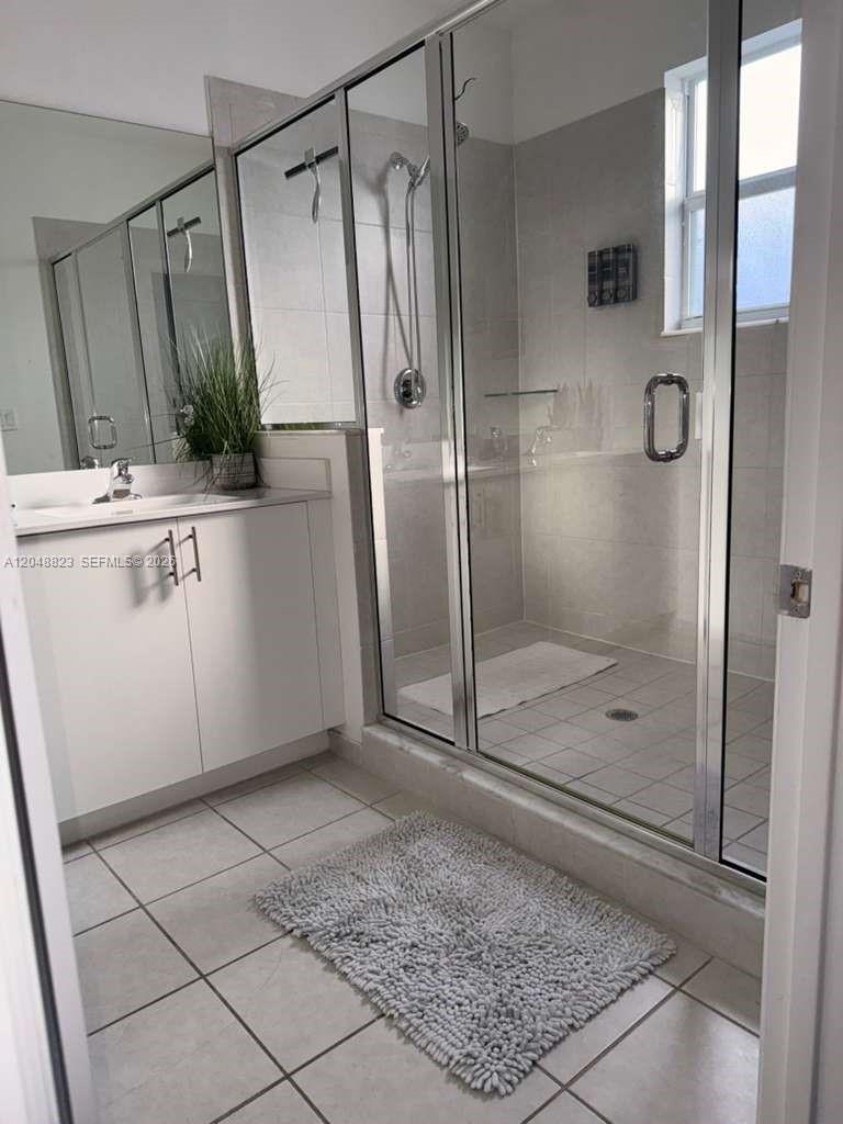 A bathroom features a white vanity, a glass-enclosed walk-in shower, and light-colored tile flooring — 13623 SW 184th Ter, Miami FL 33177, MIAMI, FL