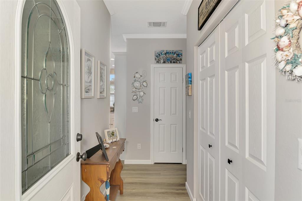 An entryway features a wood console table, light wood-look flooring, and white paneled doors — 804 TURF, VENICE, FL