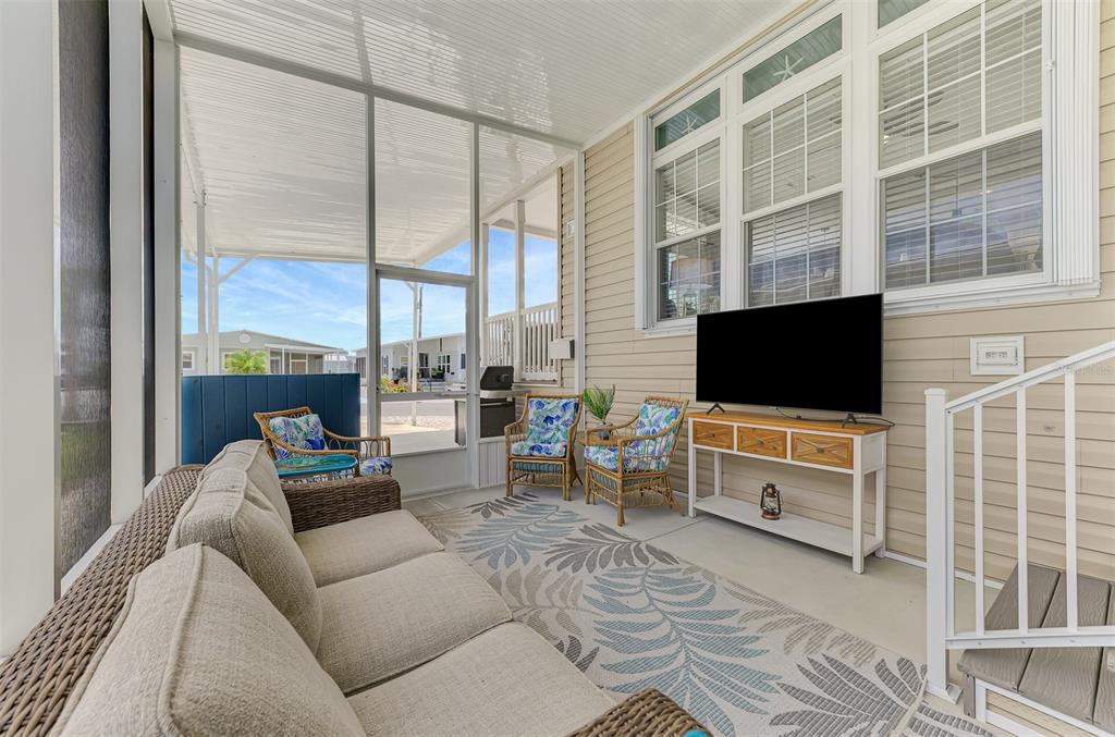 A screened-in patio features wicker furniture, a television on a console table, and a rug — 804 TURF, VENICE, FL