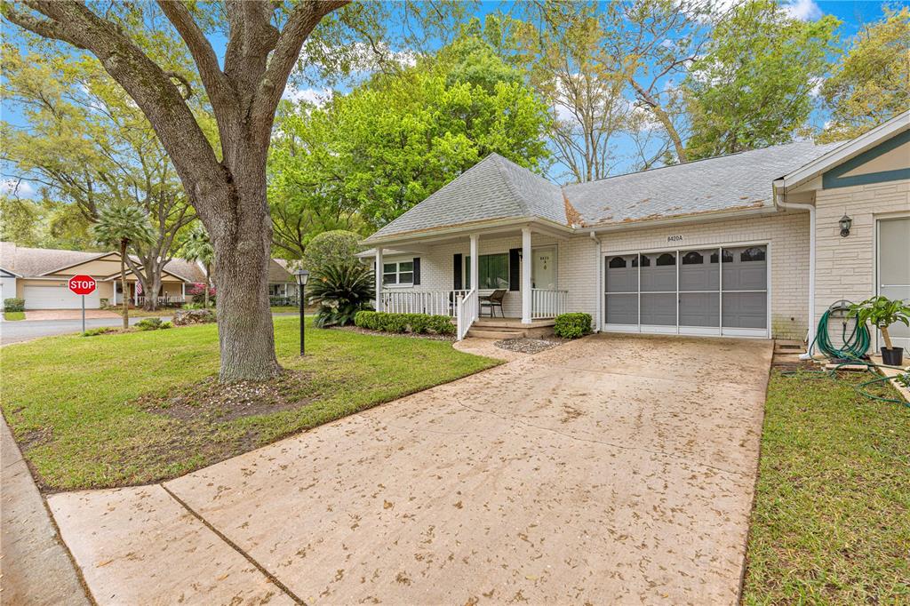 A single-story white brick house features a gray garage door and a covered front porch — 8420 SW 92ND STREET UNIT A, OCALA, FL