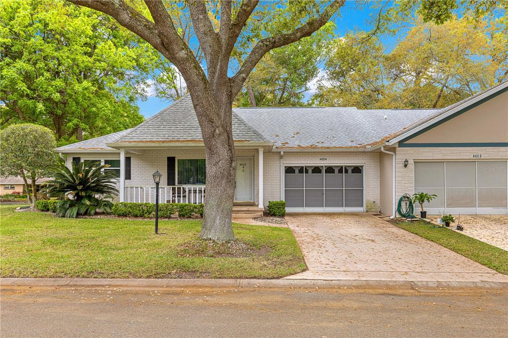 A single-story brick house with a gray shingled roof, a tree, and a driveway — 8420 SW 92ND STREET UNIT A, OCALA, FL