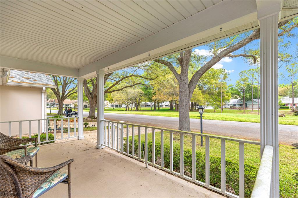 A covered porch features a concrete floor, white railings, and views of a neighborhood street — 8420 SW 92ND STREET UNIT A, OCALA, FL