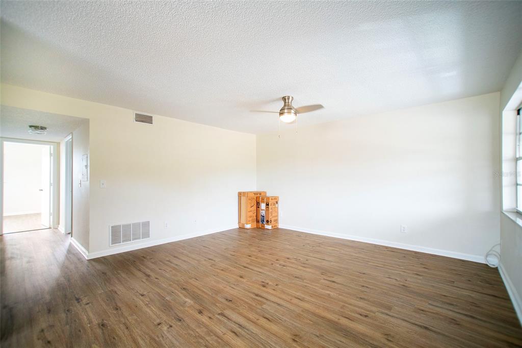An empty room with wood-look flooring, a ceiling fan, and two cardboard boxes — 6062 22ND AVENUE N UNIT 5, ST PETERSBURG, FL