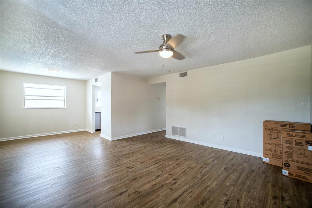 An empty living room features light-colored walls, wood-look flooring, a ceiling fan, and a window — 6062 22ND AVENUE N UNIT 5, ST PETERSBURG, FL