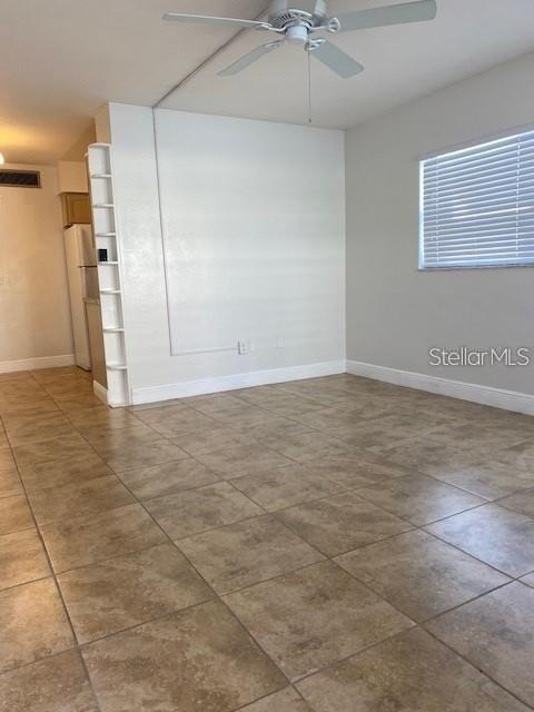 An empty room features light-colored walls, a ceiling fan, and tan tile flooring — 4565 DUHME ROAD UNIT 110, ST PETERSBURG, FL
