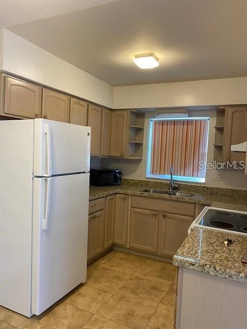 A kitchen features light wood cabinets, granite countertops, a white refrigerator, and a window — 4565 DUHME ROAD UNIT 110, ST PETERSBURG, FL