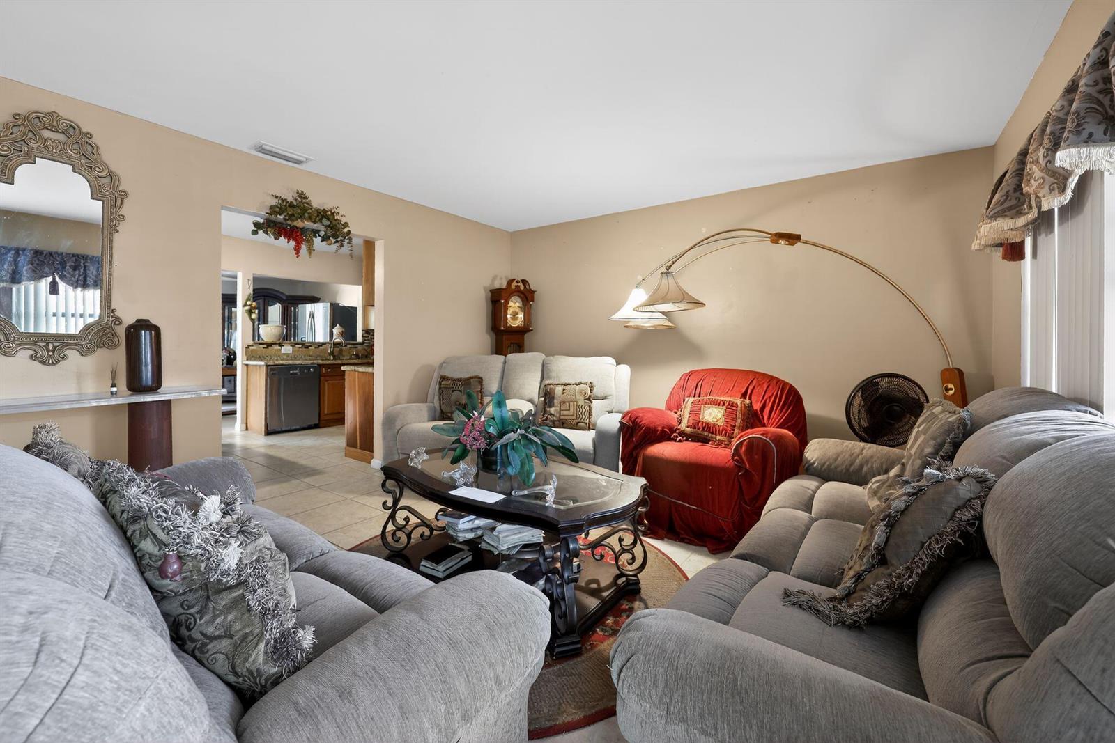 A living room features gray sofas, a red armchair, a coffee table, and a floor lamp — 9522 Affirmed Lane, Boca Raton FL 33496, BOCA RATON, FL