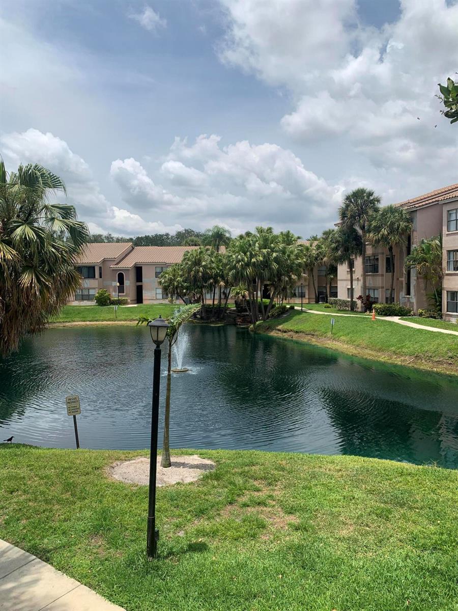 A pond with a fountain sits between apartment buildings surrounded by palm trees and grass — 2926 S University Drive # 6202, Davie FL 33328, DAVIE, FL