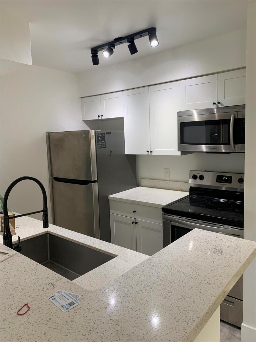A kitchen features white cabinets, stainless steel appliances, and light speckled countertops — 2926 S University Drive # 6202, Davie FL 33328, DAVIE, FL