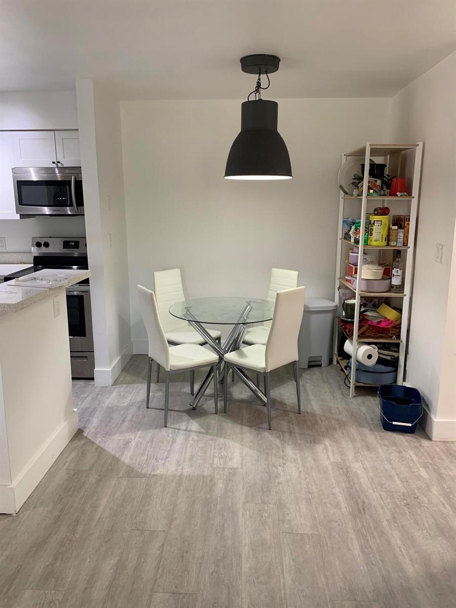 A dining area features a glass-top table, four white chairs, and a black pendant light — 2926 S University Drive # 6202, Davie FL 33328, DAVIE, FL