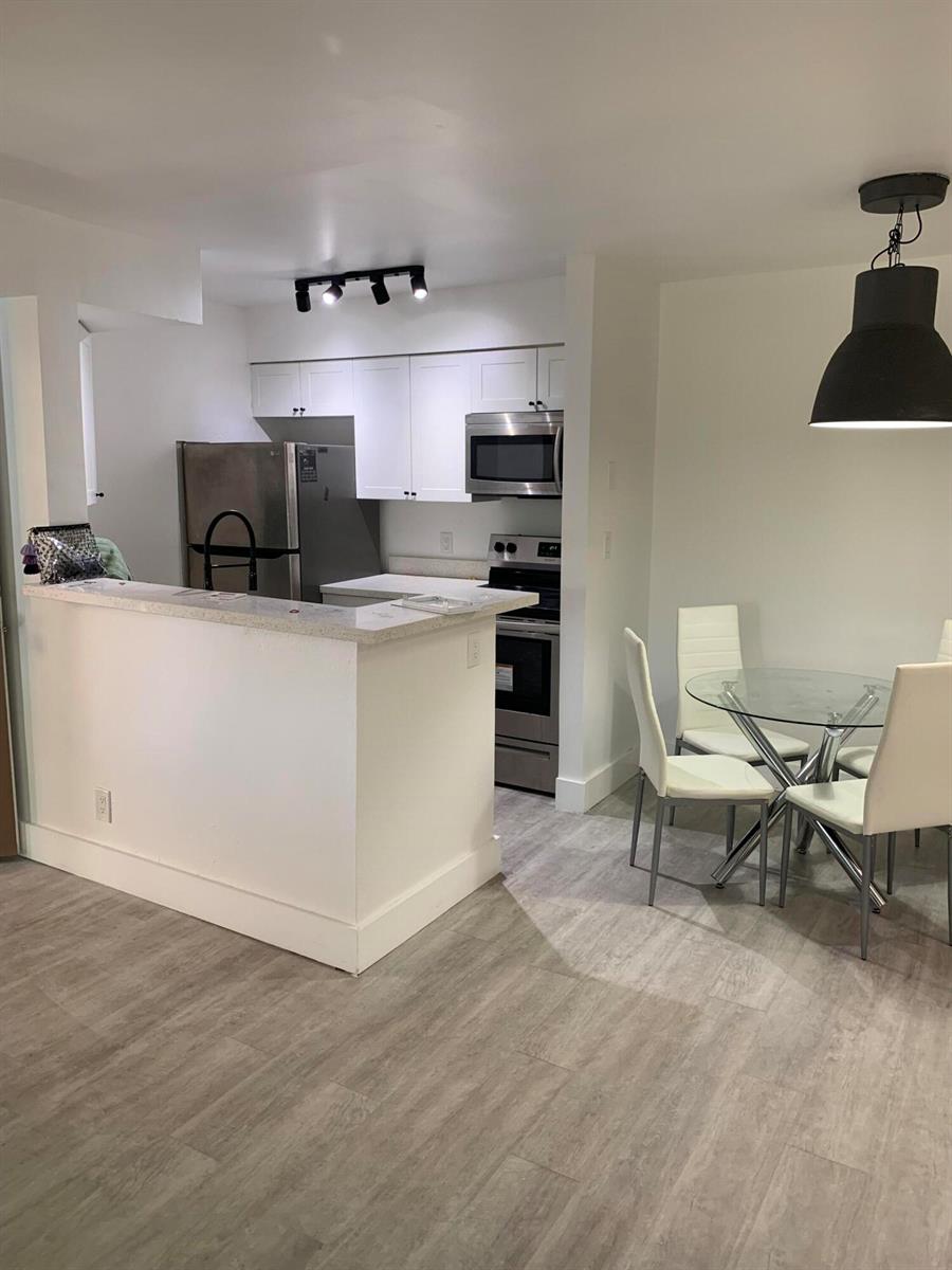 A kitchen with white cabinets and stainless steel appliances sits next to a dining area — 2926 S University Drive # 6202, Davie FL 33328, DAVIE, FL