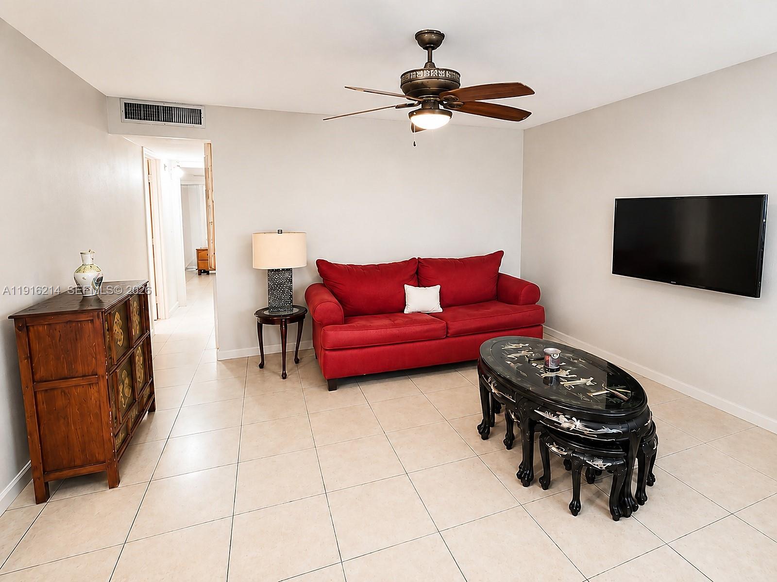 A living room features a red sofa, a black coffee table, and a wooden cabinet — 116 Tuscany B # 116, Delray Beach FL 33446, DELRAY BEACH, FL