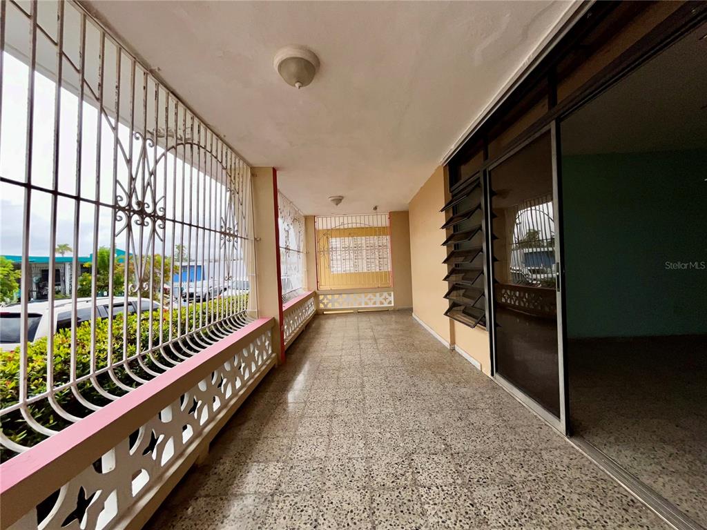 A covered outdoor patio features a terrazzo floor, metal security bars, and sliding glass doors — Urb Santa Isidra 2 #130, FAJARDO, PR