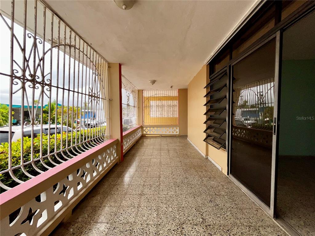 A covered outdoor patio with a tiled floor, metal security bars, and sliding glass doors — Urb Santa Isidra 2 #130, FAJARDO, PR