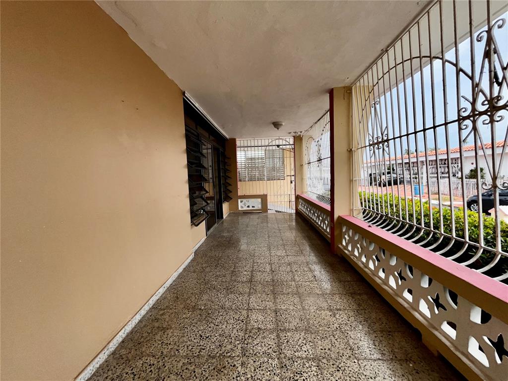 A covered outdoor patio features speckled tile flooring, a decorative concrete railing, and metal security bars — Urb Santa Isidra 2 #130, FAJARDO, PR