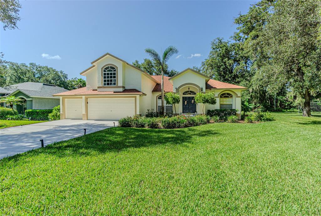 A two-story house with a beige exterior, a two-car garage, and a large front lawn — 2409 FOX FOREST DRIVE, LUTZ, FL