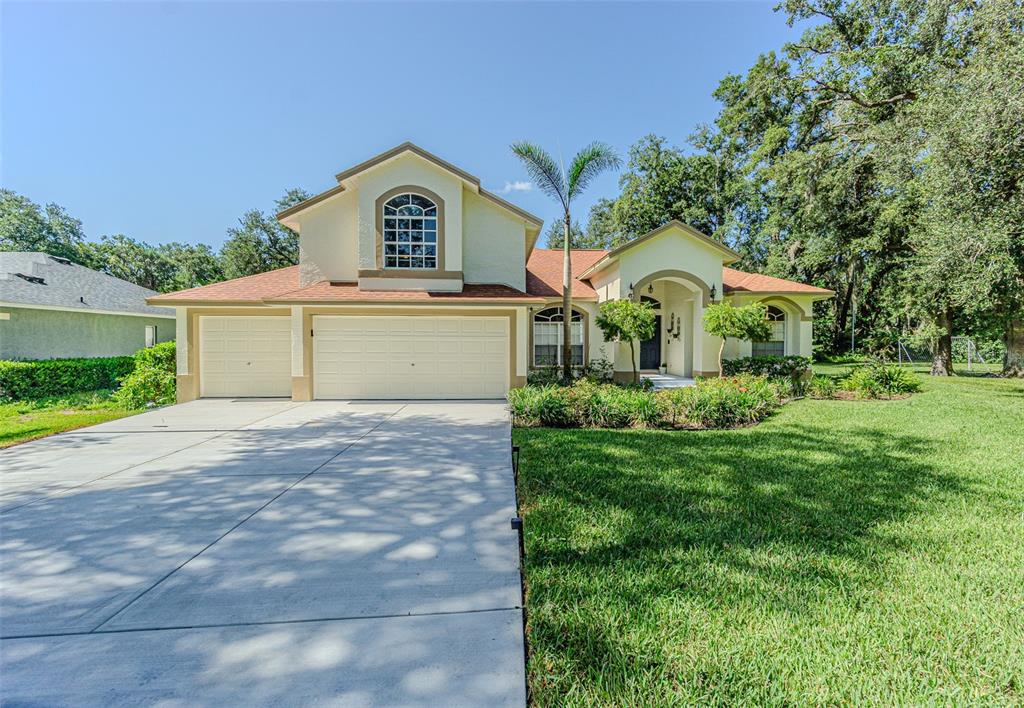 A two-story house with a three-car garage, a concrete driveway, and a landscaped front yard — 2409 FOX FOREST DRIVE, LUTZ, FL