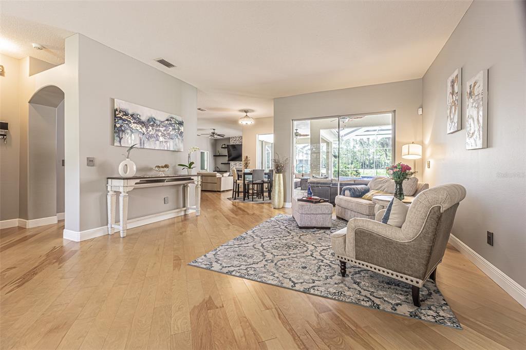 A living room with light wood floors, a patterned area rug, and an entryway — 2409 FOX FOREST DRIVE, LUTZ, FL
