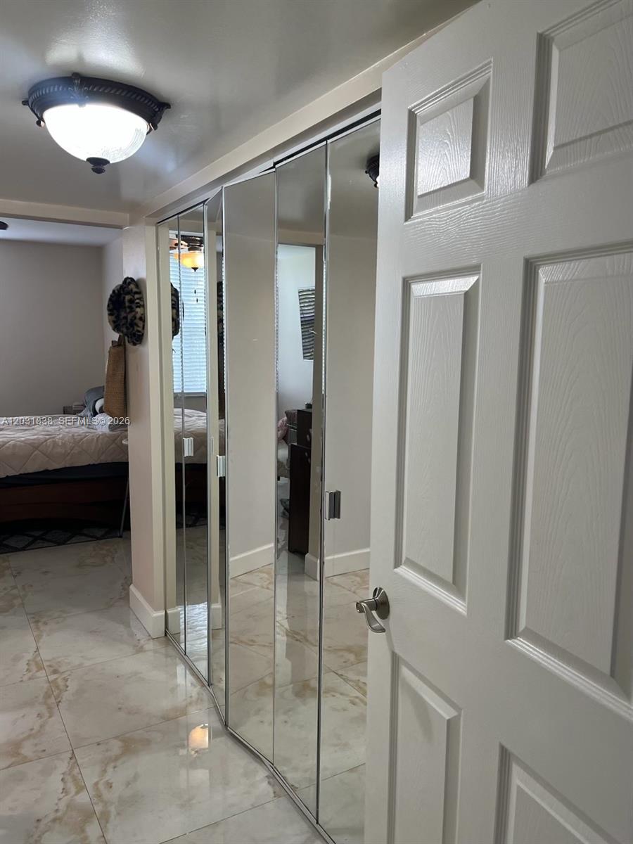 A hallway features light-colored tile flooring, a ceiling light fixture, and mirrored closet doors — 9420 Tangerine Pl # 401, Davie FL 33324, DAVIE, FL