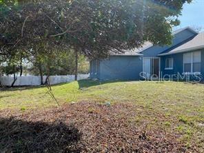A blue house with a white fence stands in a grassy yard under a tree — 1551 ORTEGA AVENUE, DELTONA, FL