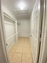 A walk-in closet with white shelving, tile flooring, and a ceiling access panel — 1551 ORTEGA AVENUE, DELTONA, FL