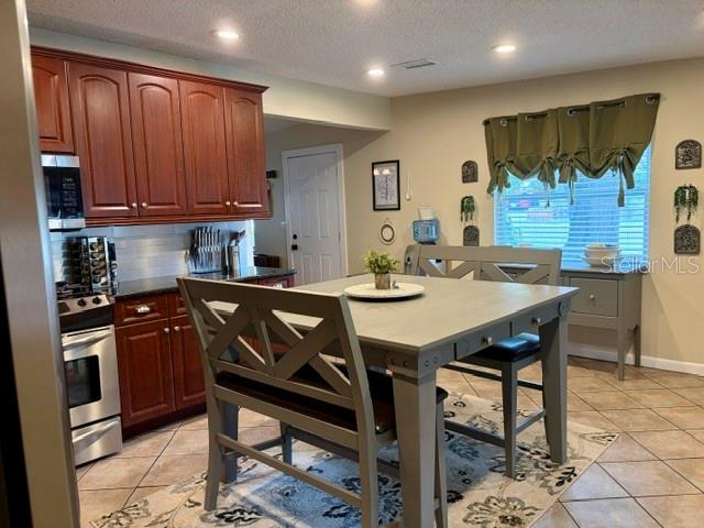 A kitchen features wooden cabinets, stainless steel appliances, and a gray dining table with chairs — 915 HARBOR HILL DRIVE, SAFETY HARBOR, FL