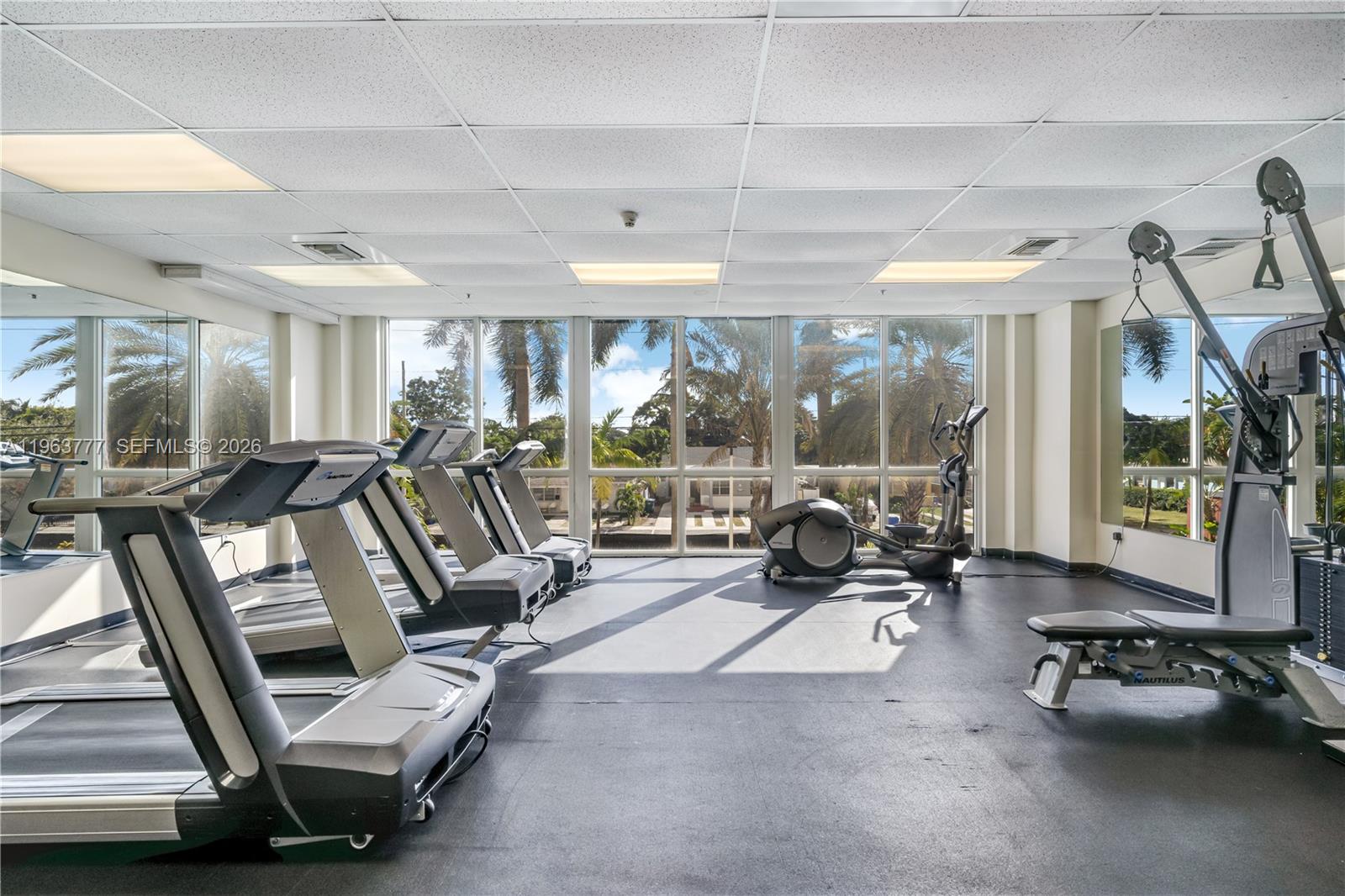 A fitness room features treadmills, an elliptical machine, a weight station, and large windows — 3500 Coral Way # 1207, Miami FL 33145, MIAMI, FL