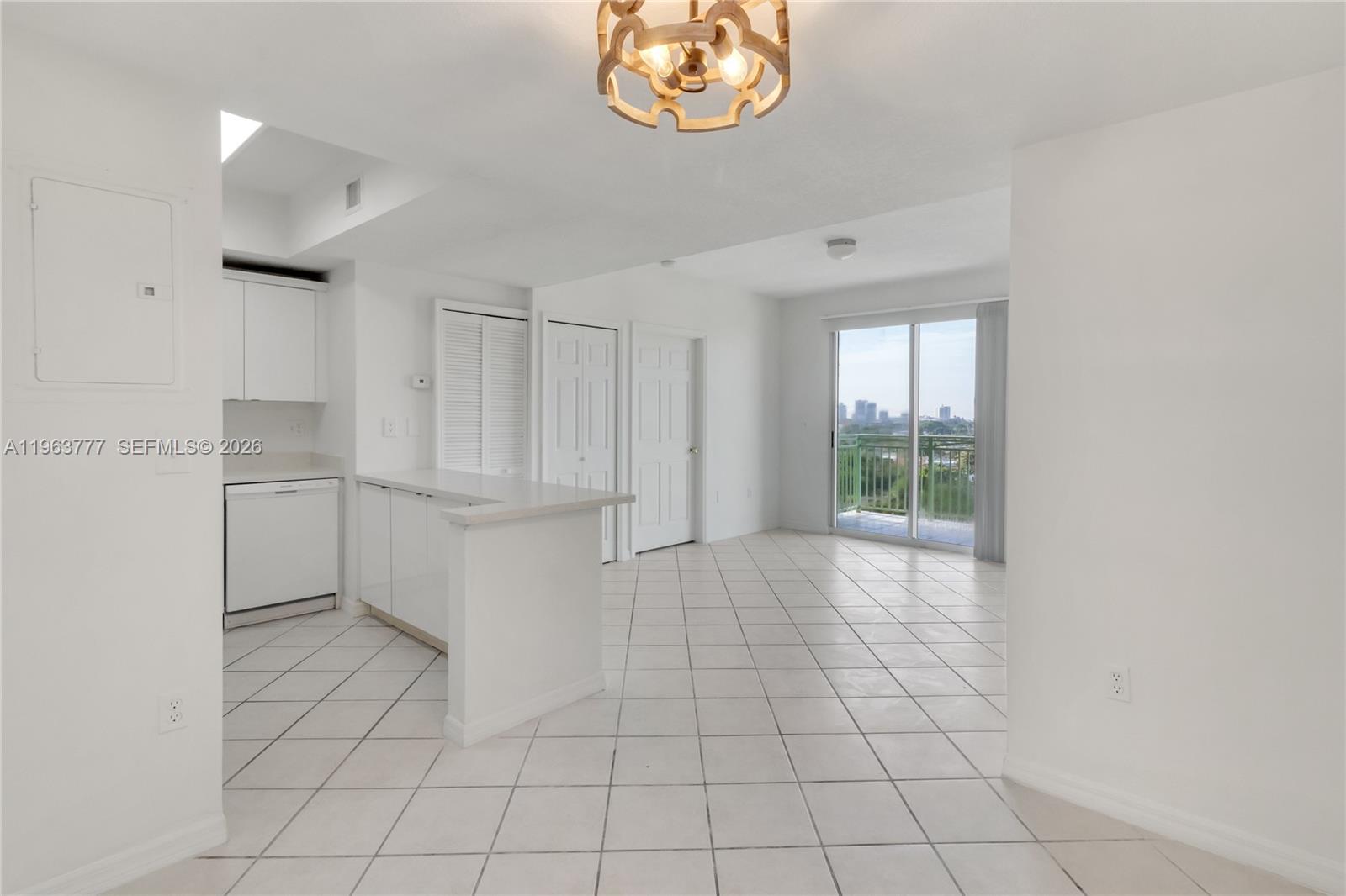 A white-tiled kitchen and living area features a breakfast bar and a balcony view — 3500 Coral Way # 1207, Miami FL 33145, MIAMI, FL