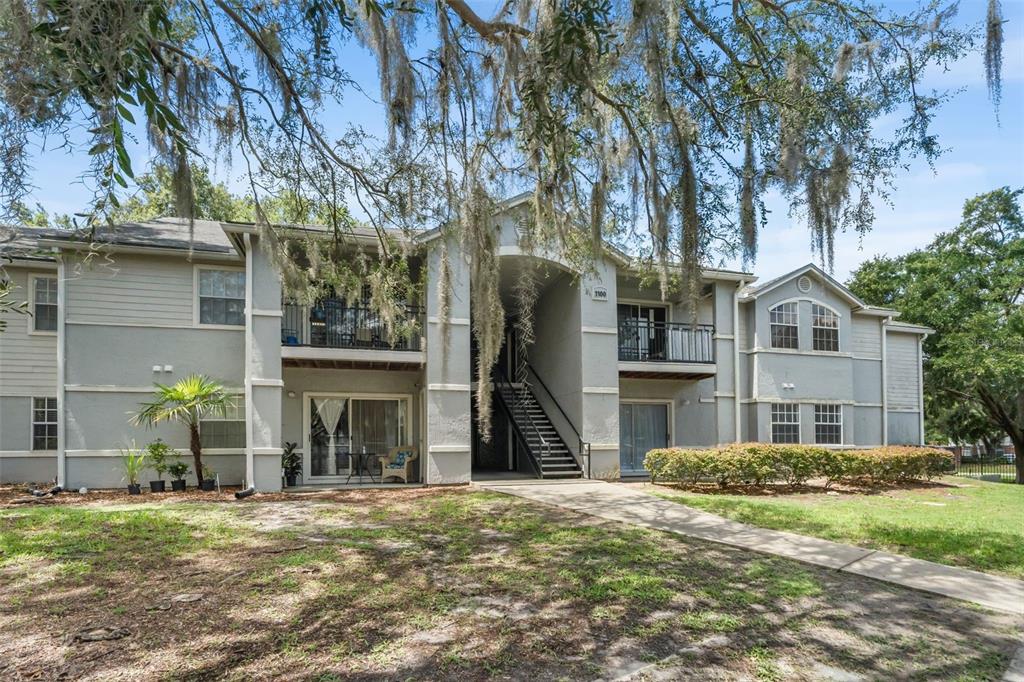 A two-story apartment building with gray stucco siding, balconies, and a central outdoor staircase — 3705 SW 27TH STREET UNIT 1117, GAINESVILLE, FL