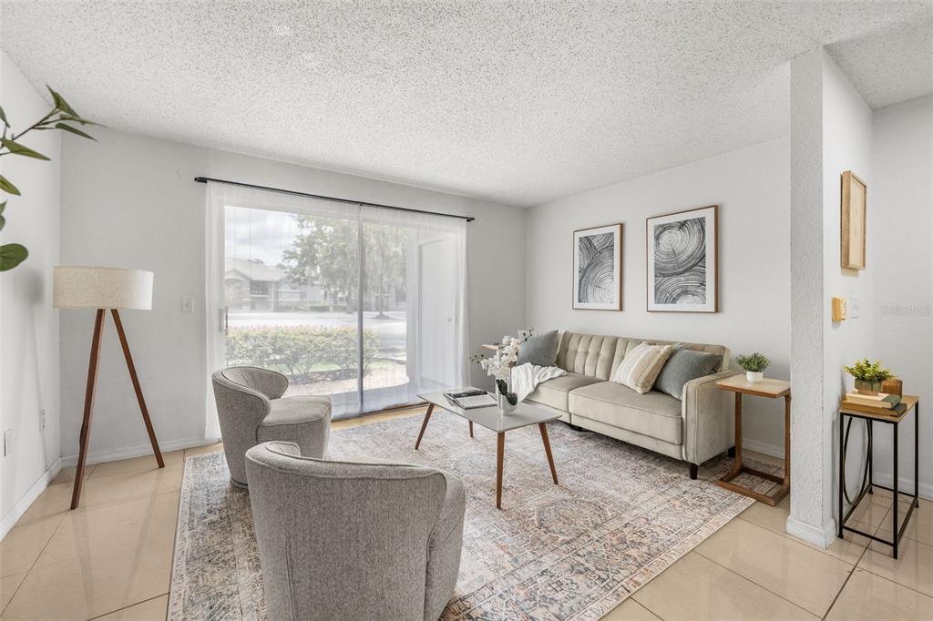 A living room features a beige sofa, two armchairs, a coffee table, and sliding glass doors — 3705 SW 27TH STREET UNIT 1117, GAINESVILLE, FL