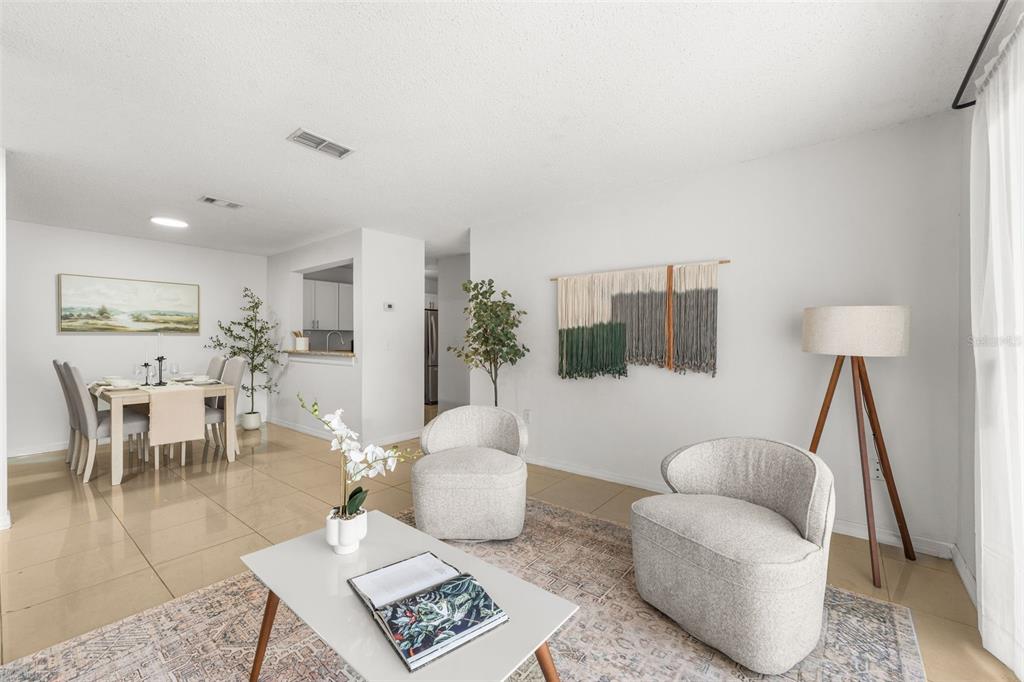 A living room and dining area with light tile floors, neutral furniture, and wall decor — 3705 SW 27TH STREET UNIT 1117, GAINESVILLE, FL