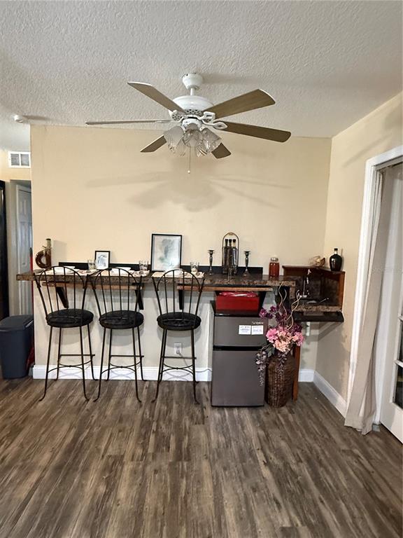 A dining area features a wall-mounted bar counter with three metal stools and a mini-fridge — 1405 JACKSON AVENUE, DAYTONA BEACH, FL