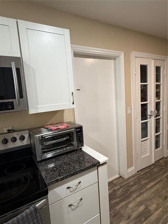 A kitchen features white cabinets, a stainless steel toaster oven, and a glass-paneled pantry door — 1405 JACKSON AVENUE, DAYTONA BEACH, FL