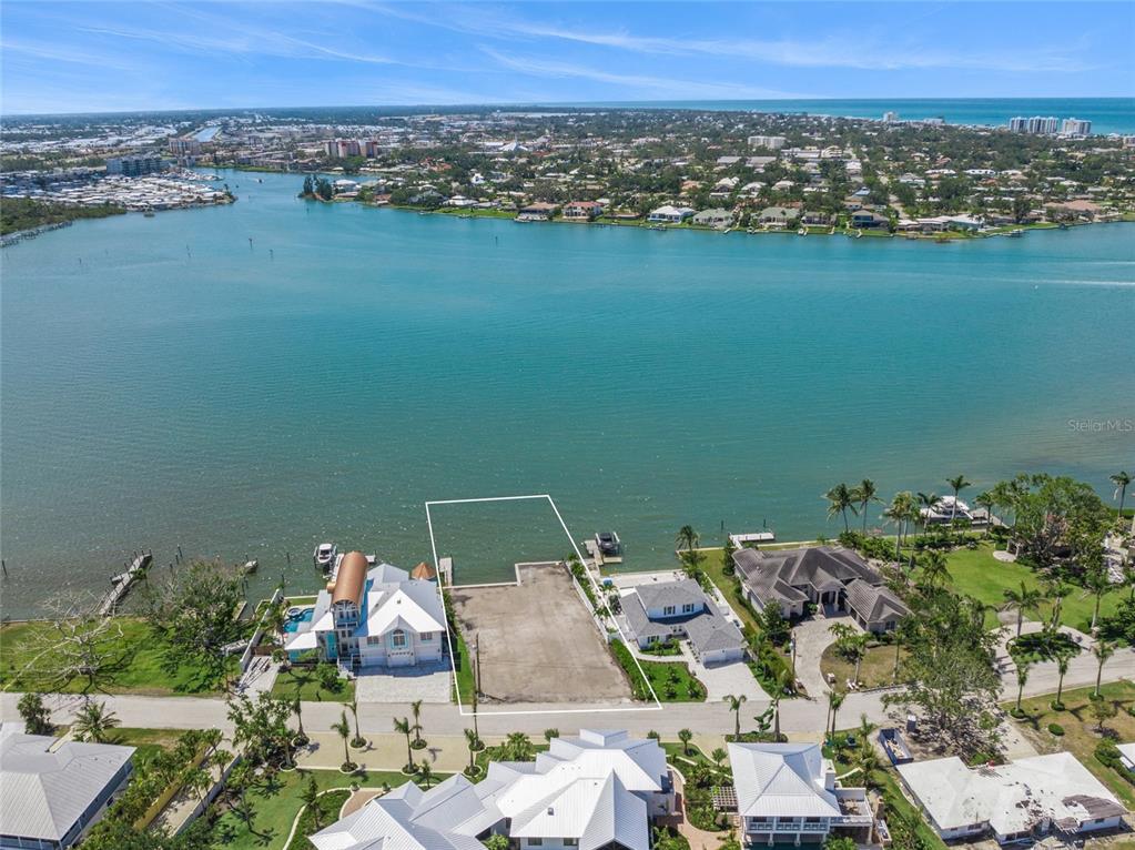 An aerial view shows a vacant waterfront lot situated between two residential homes — 325 SUNRISE DRIVE, NOKOMIS, FL