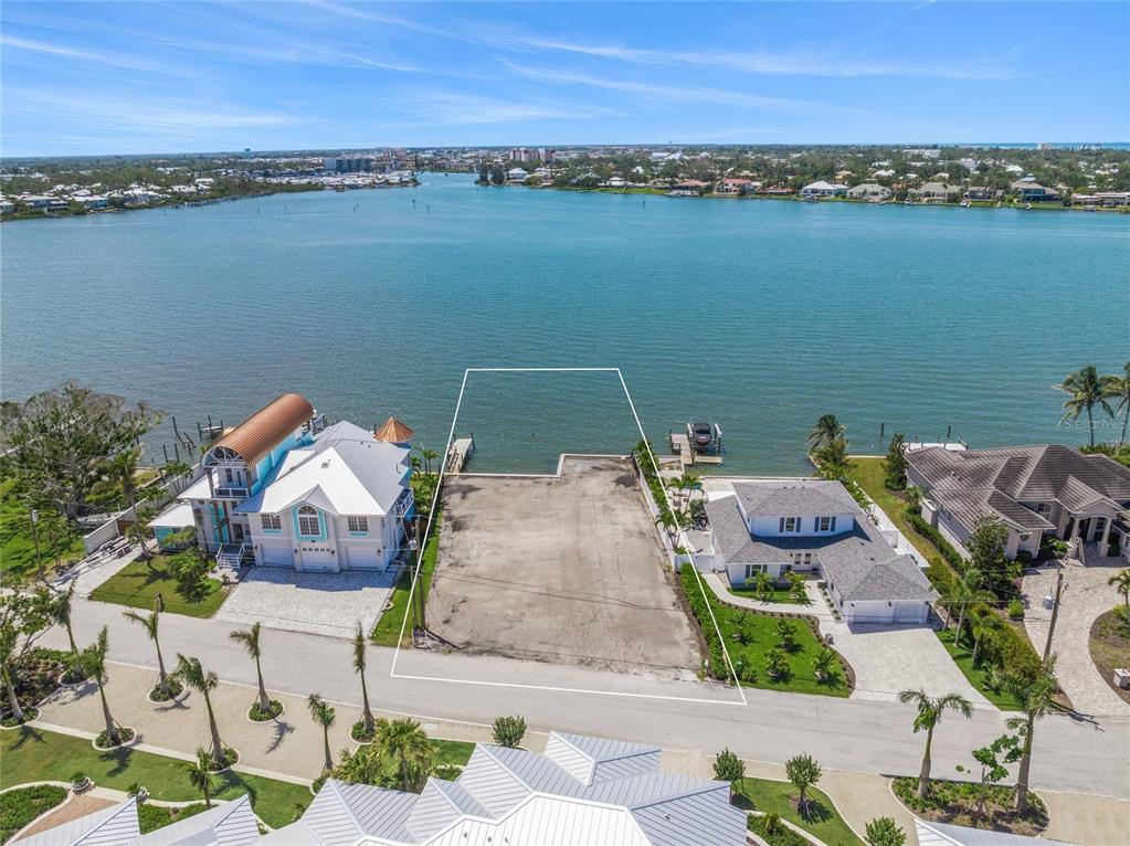 An aerial view of a vacant waterfront lot situated between two houses on a bay — 325 SUNRISE DRIVE, NOKOMIS, FL