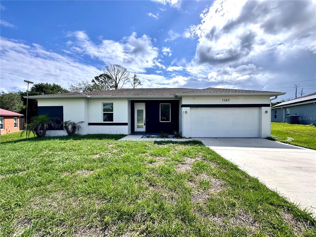 A single-story house with a white exterior, dark accents, and a two-car garage — 1389 WORTHINGTON DRIVE, DELTONA, FL