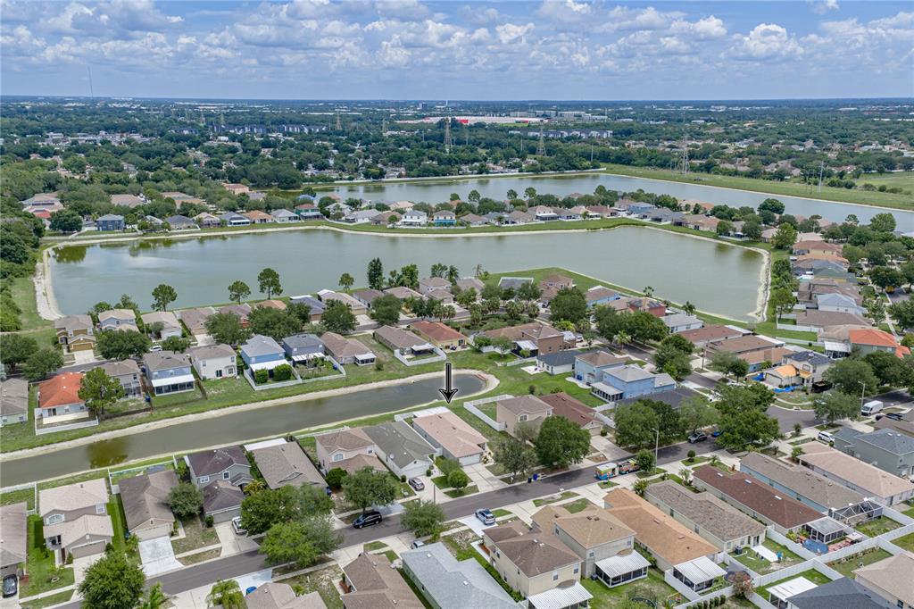 An aerial view shows a suburban neighborhood with houses surrounding a long, narrow retention pond — 8160 CANTERBURY LAKE BOULEVARD, TAMPA, FL