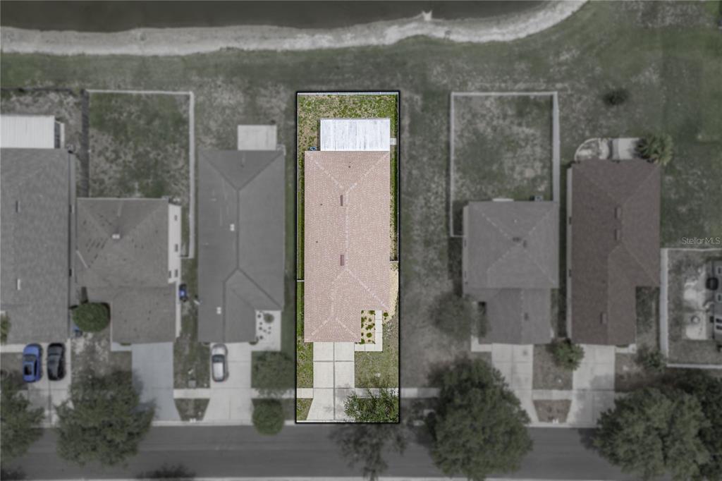 An aerial view shows a single-family home with a backyard patio facing a lake — 8160 CANTERBURY LAKE BOULEVARD, TAMPA, FL