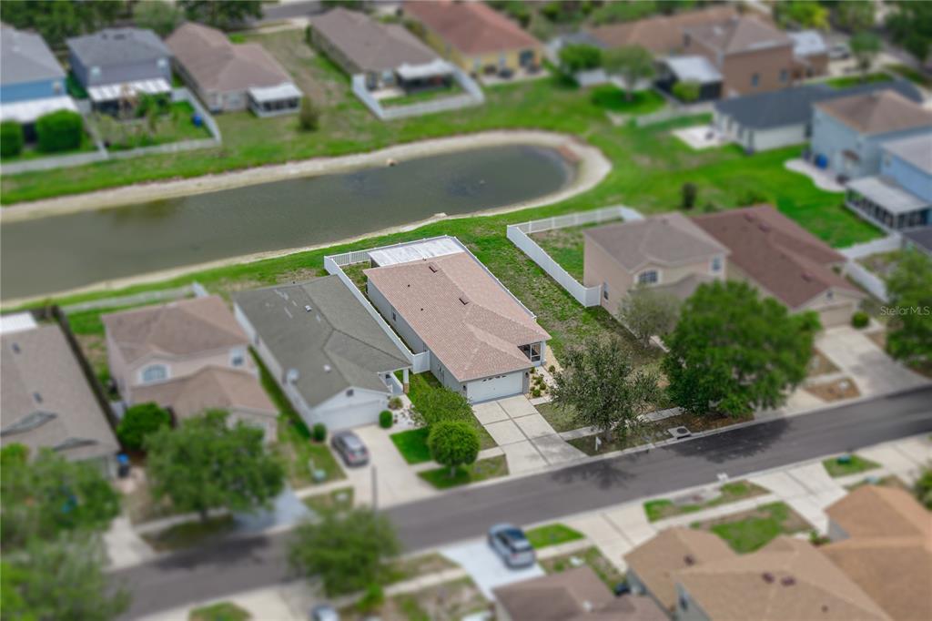 An aerial view shows a suburban house with a tan roof and a backyard pond — 8160 CANTERBURY LAKE BOULEVARD, TAMPA, FL