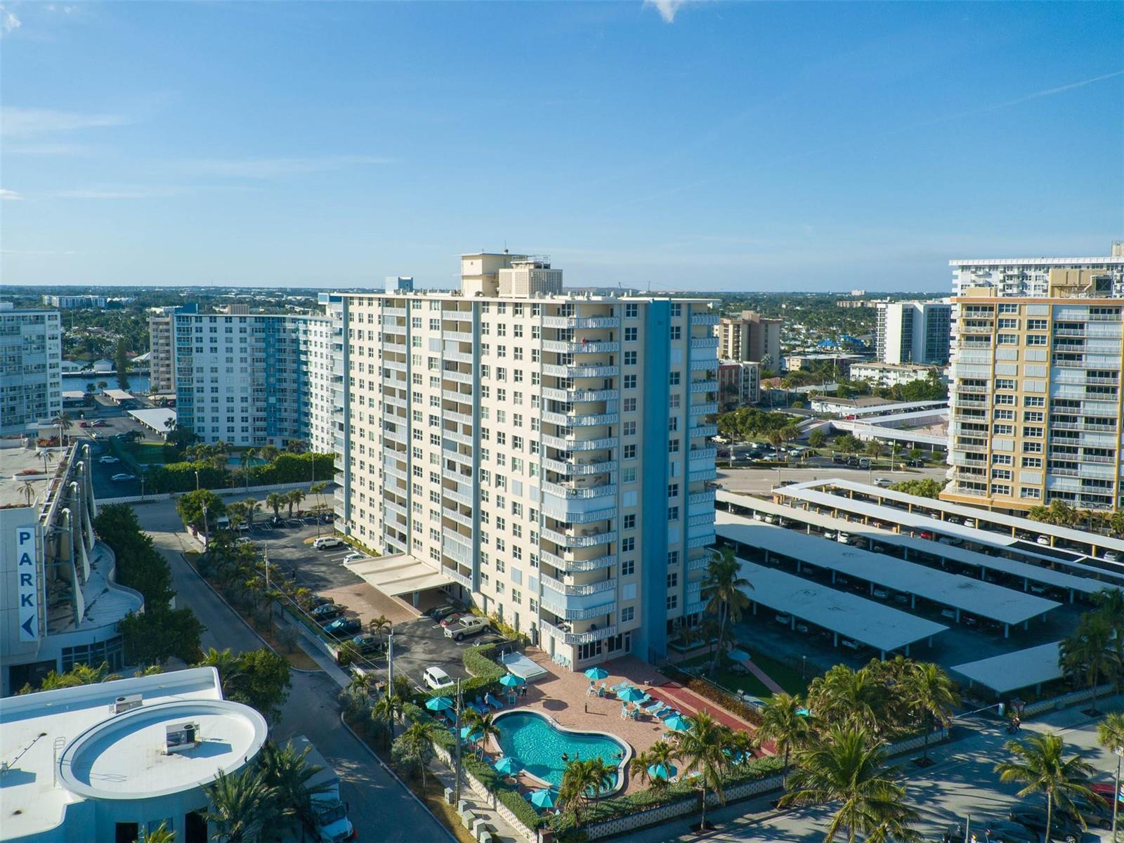 An aerial view shows a multi-story apartment building with a pool and parking structure — 305 N Pompano Beach Boulevard # 505, Pompano Beach FL 33062, POMPANO BEACH, FL