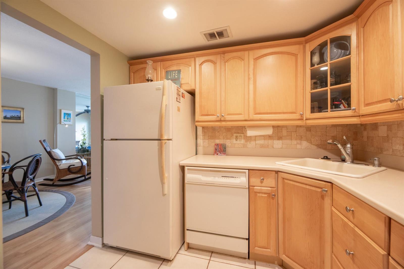 A kitchen features light wood cabinets, a white refrigerator, a dishwasher, and a tiled backsplash — 305 N Pompano Beach Boulevard # 505, Pompano Beach FL 33062, POMPANO BEACH, FL