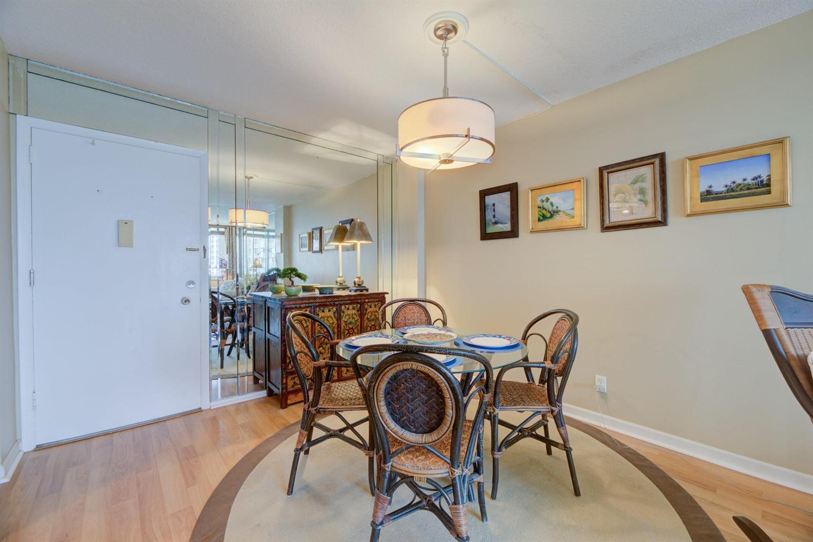 A dining area features a glass-topped table, four wicker chairs, a mirrored wall, and artwork — 305 N Pompano Beach Boulevard # 505, Pompano Beach FL 33062, POMPANO BEACH, FL