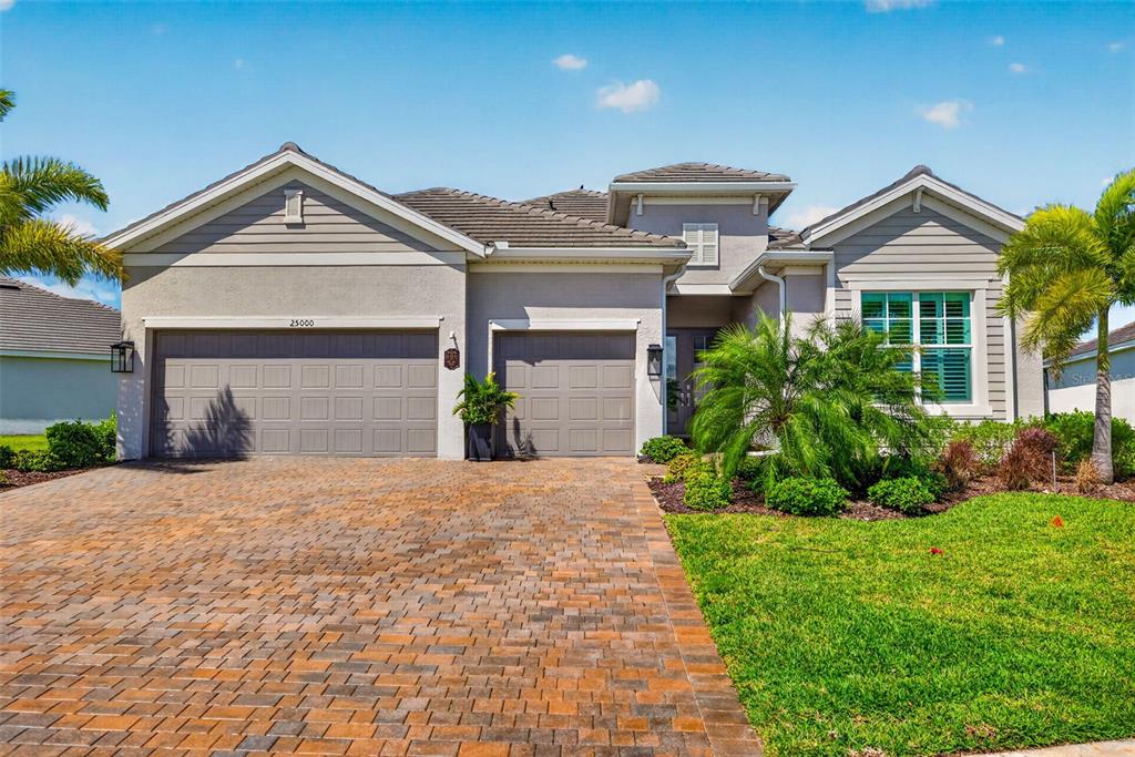 A single-story house with a paved driveway, two garage doors, and palm trees — 25000 HALLIANA LANE, PUNTA GORDA, FL