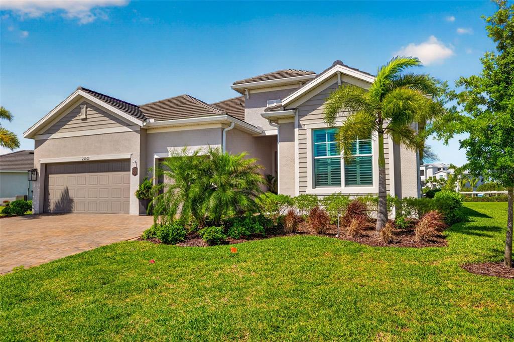 A single-story suburban house with a paved driveway, a two-car garage, and a palm tree — 25000 HALLIANA LANE, PUNTA GORDA, FL