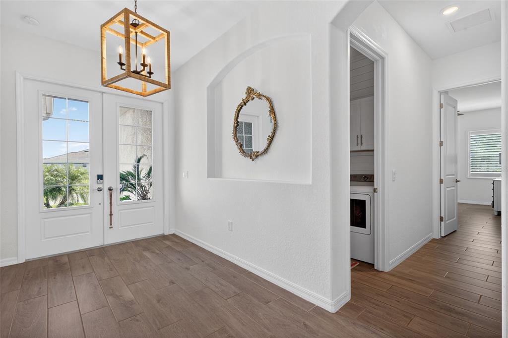 A bright entryway features wood-look tile flooring, a lantern pendant light, and an arched wall niche — 25000 HALLIANA LANE, PUNTA GORDA, FL