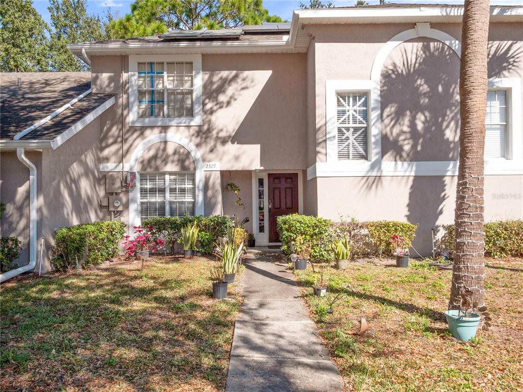 The exterior of a two-story tan house features a front walkway, landscaping, and a brown door — 2329 WATER VIEW LOOP, KISSIMMEE, FL
